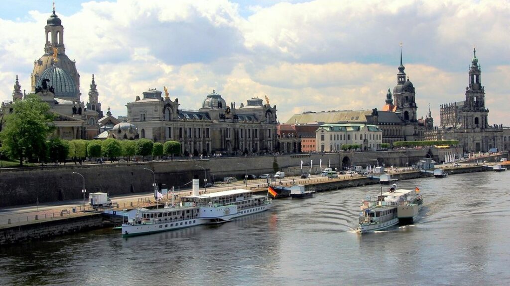 Les berges de l'Elbe avec des bateaux de croisière, la coupole d'une église et un clocher au-dessus des toits