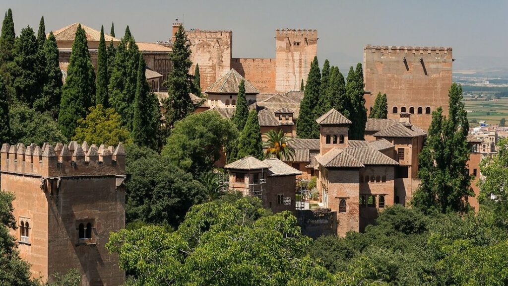 Tours et toits ocre de l'Alhambra émergeant des cyprès et des jardins du Generalife