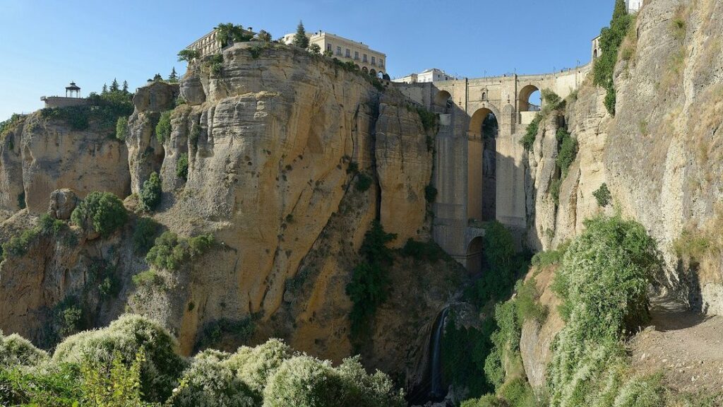 Pont de pierre enjambant la gorge du Tajo entre deux falaises à Ronda, avec la ville au sommet