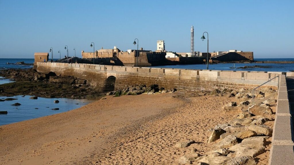 Château de San Sebastián au bout d'une jetée de pierre, sur une plage de sable à marée basse à Cadix