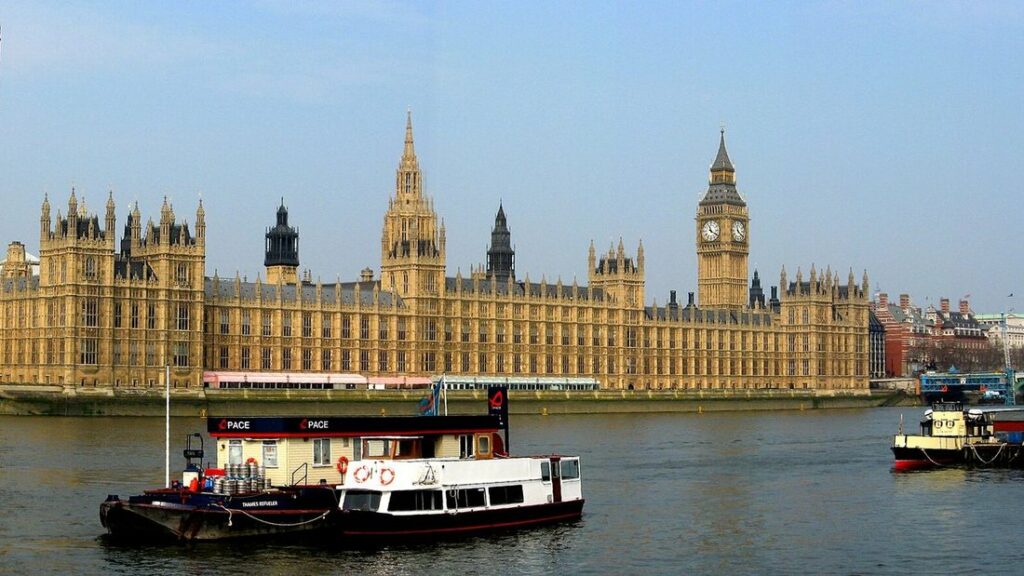 Le Palais de Westminster et la tour de Big Ben au bord de la Tamise, avec un bateau sur l'eau