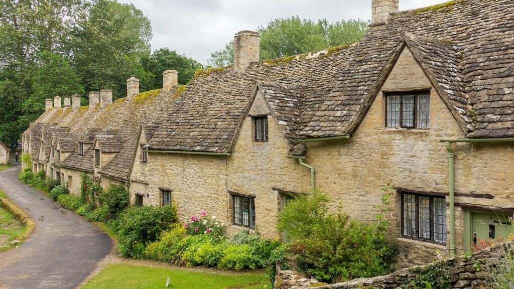 Maisons de pierre claire aux toits de dalles le long d'une petite route de campagne à Bibury
