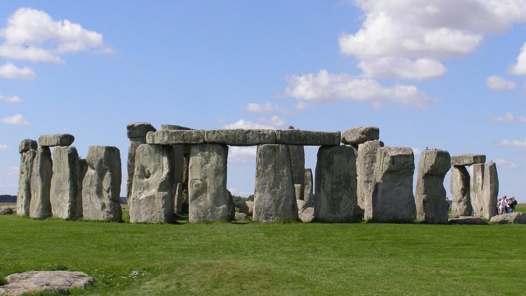 Le cercle de pierres dressées de Stonehenge sur une pelouse verte, sous un ciel bleu et nuageux