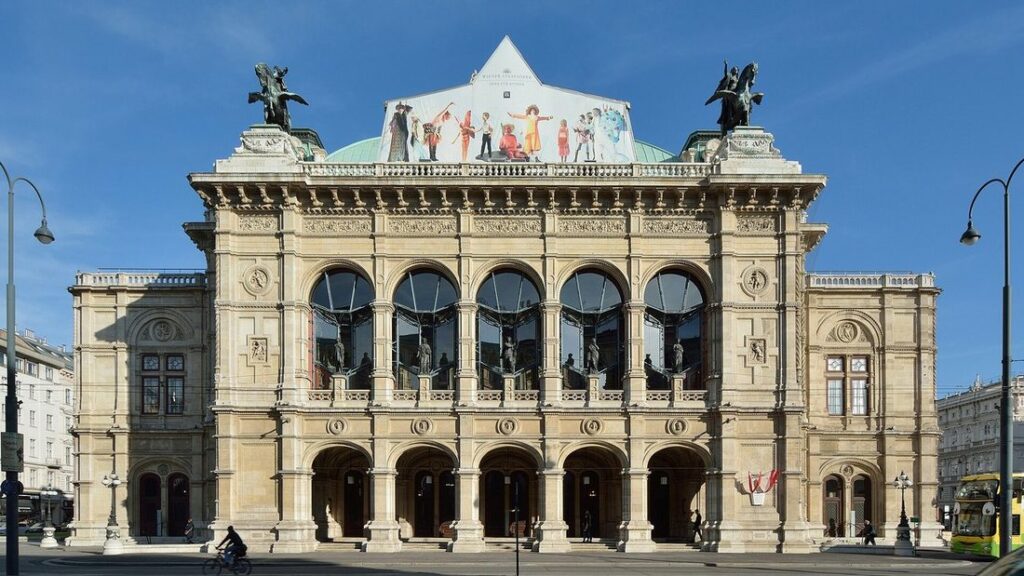 Façade en pierre claire de l'Opéra d'État de Vienne, avec ses arcades, sous un ciel bleu