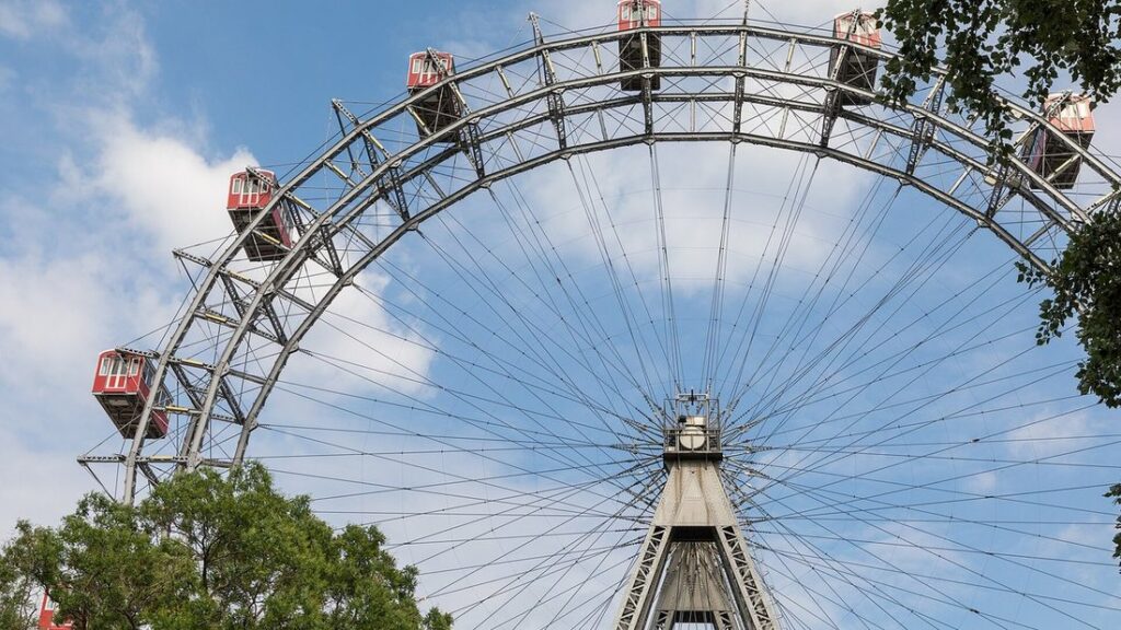 Arcs métalliques de la grande roue du Prater avec ses nacelles rouges, sous un ciel bleu