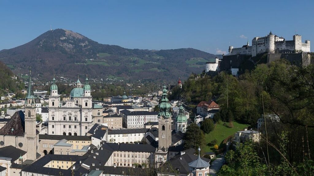Toits et clochers de la vieille ville de Salzbourg, avec la forteresse sur sa colline et des montagnes au fond