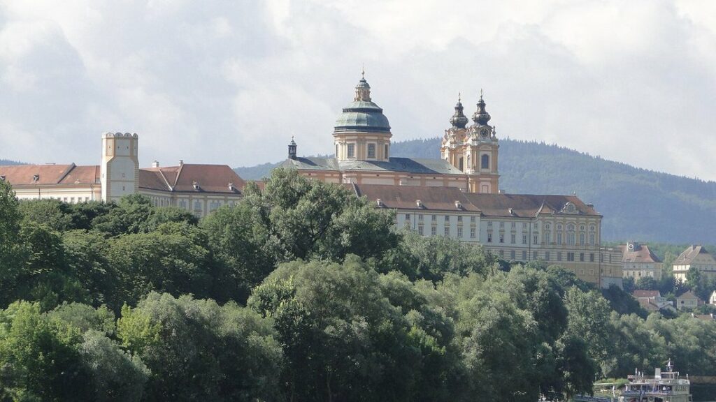 Clochers et toits de l'abbaye de Melk sur une colline boisée, au-dessus du Danube