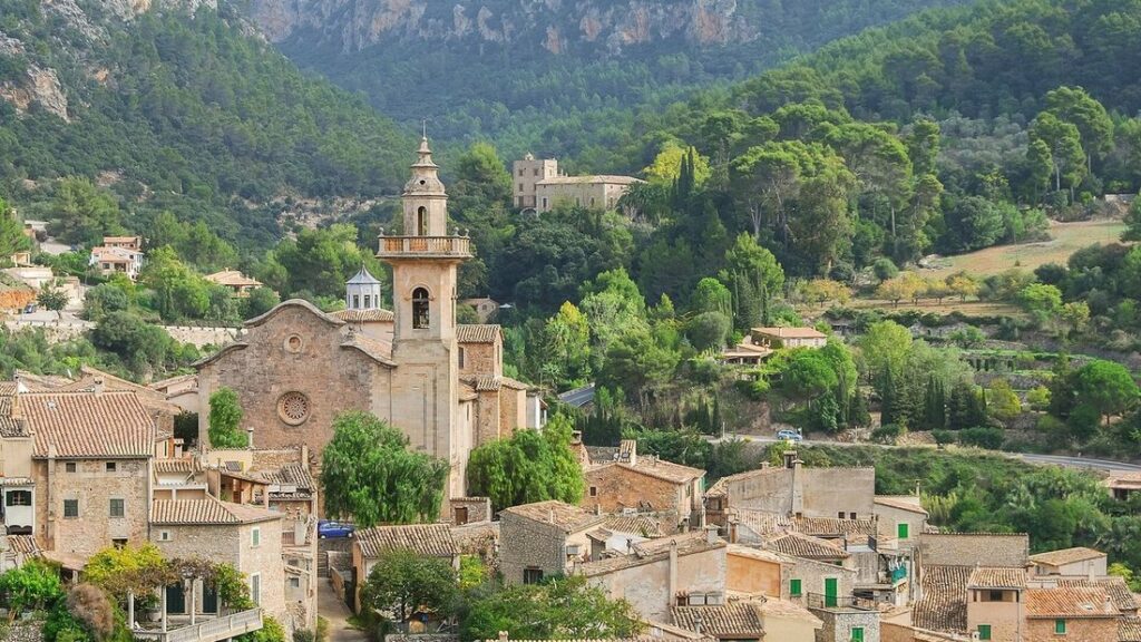 Toits de tuiles de Valldemossa autour du clocher de l'église, entourés de collines boisées