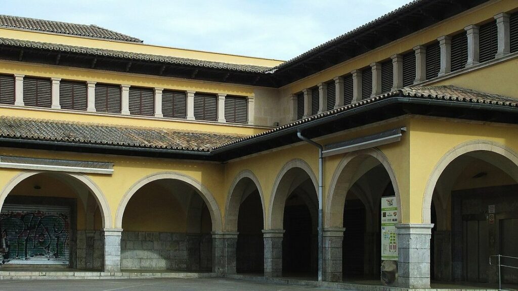 Façade jaune à arcades et toit de tuiles d'un grand bâtiment de marché couvert, sous un ciel dégagé
