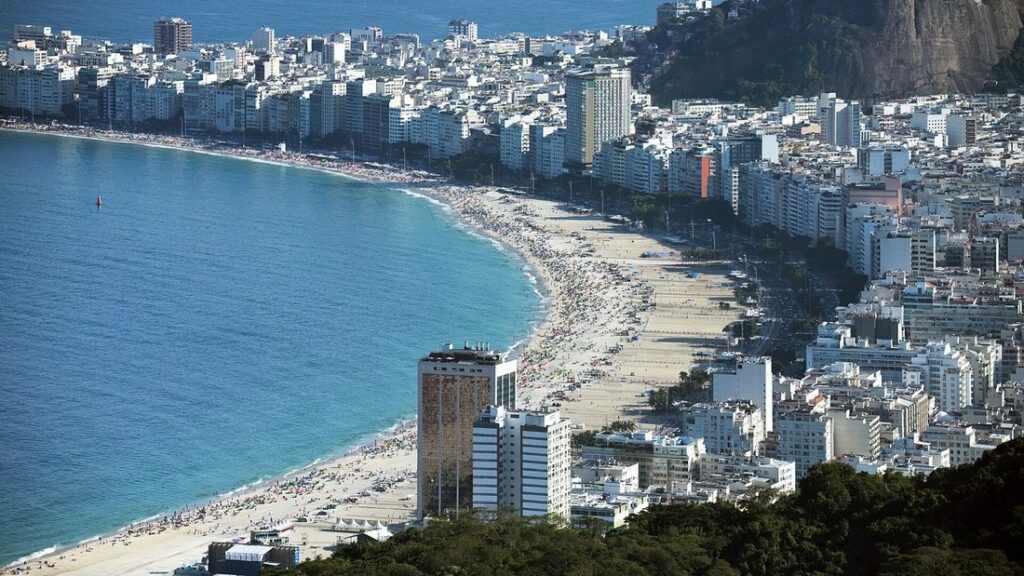 Vue plongeante sur la longue courbe de sable de Copacabana, bordée d'immeubles, au bord d'une mer bleu-vert