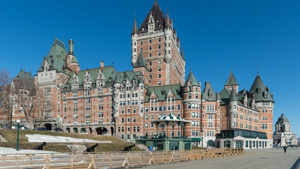 Le Château Frontenac, édifice de brique aux toits de cuivre vert et à la haute tour, sous un ciel bleu