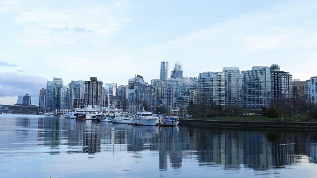Tours résidentielles et marina de Vancouver reflétées dans l'eau calme, vues depuis le bord de Stanley Park