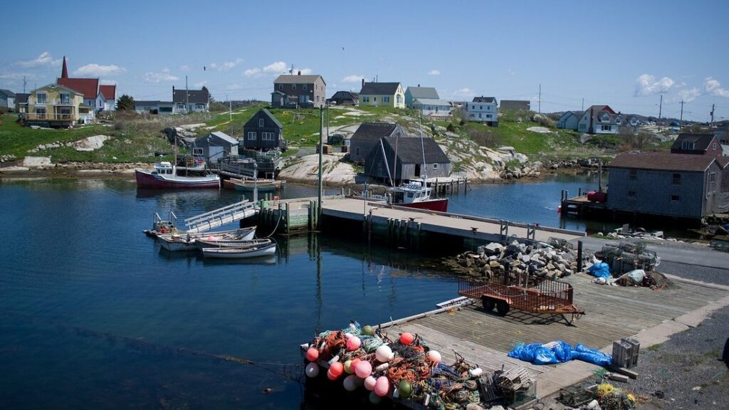 Port de pêche de Peggys Cove avec des bateaux amarrés, des quais de bois, des bouées et des maisons sur la rive