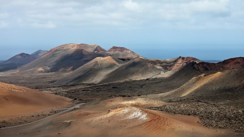 Cônes volcaniques aux pentes rouges et ocre dans le parc national de Timanfaya, sous un ciel voilé