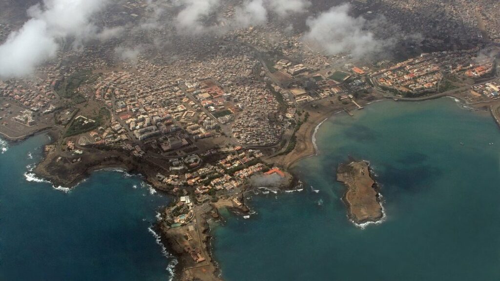 Vue aérienne de la ville de Praia sur son plateau, avec la côte rocheuse et un îlot au large