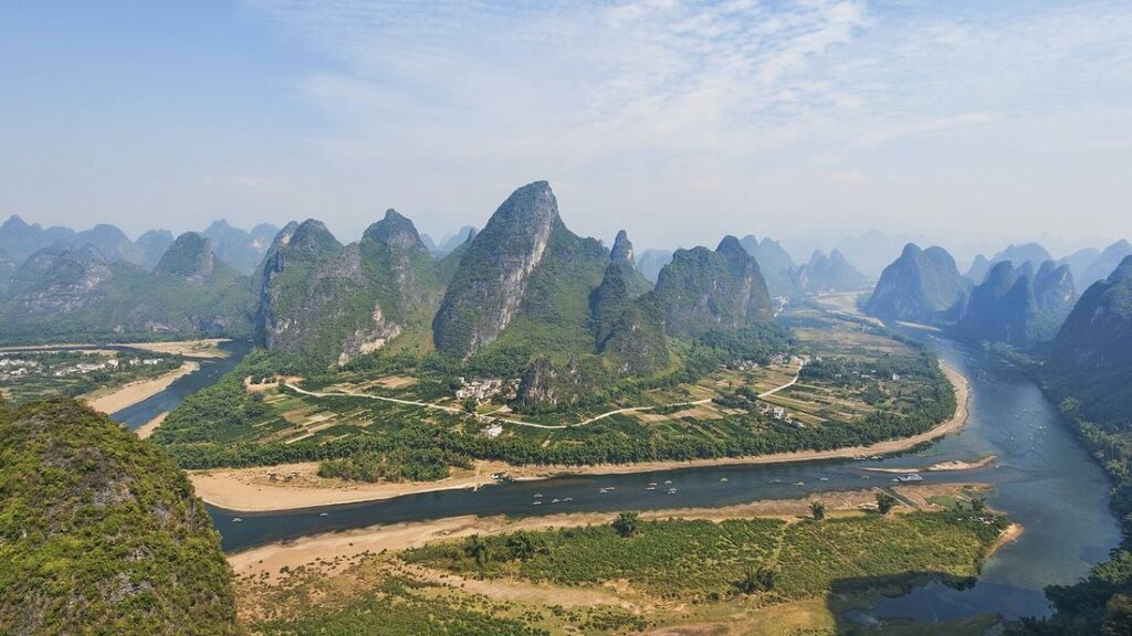 Rivière sinueuse entre rizières et pitons calcaires verts, vue depuis un point de vue en hauteur