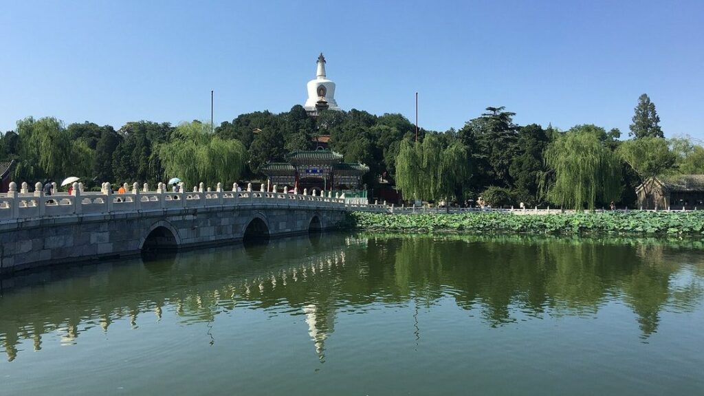 Lac bordé de saules et pont de pierre, avec la pagode blanche qui domine l'île au fond