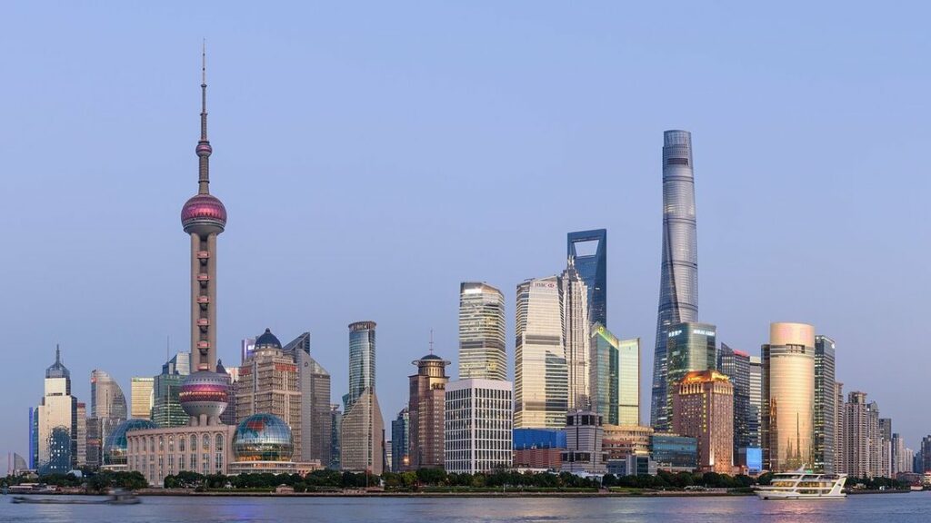 Gratte-ciel de Pudong et tour à sphères roses au bord du fleuve, sous un ciel dégagé