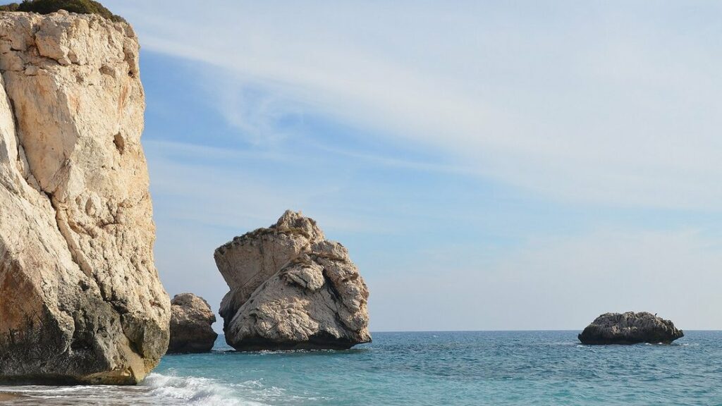 Falaise et gros rocher au bord de la mer, sous un ciel bleu, à Petra tou Romiou