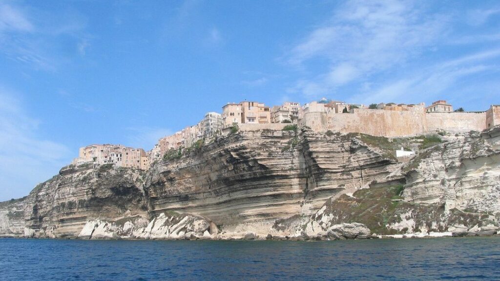 Maisons et remparts de la haute ville de Bonifacio au bord d'une falaise de calcaire stratifié, vus depuis la mer
