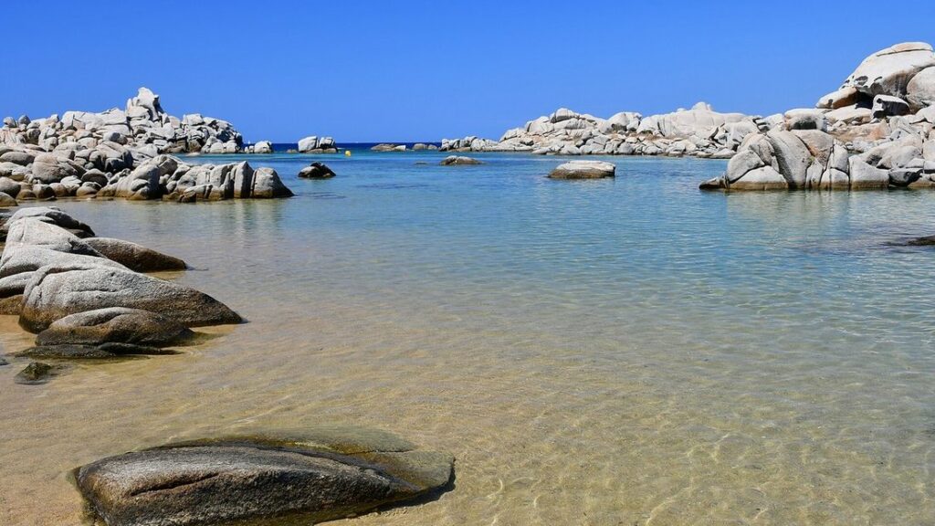 Rochers de granit clair et eau limpide à fond sableux sur une plage des îles Lavezzi