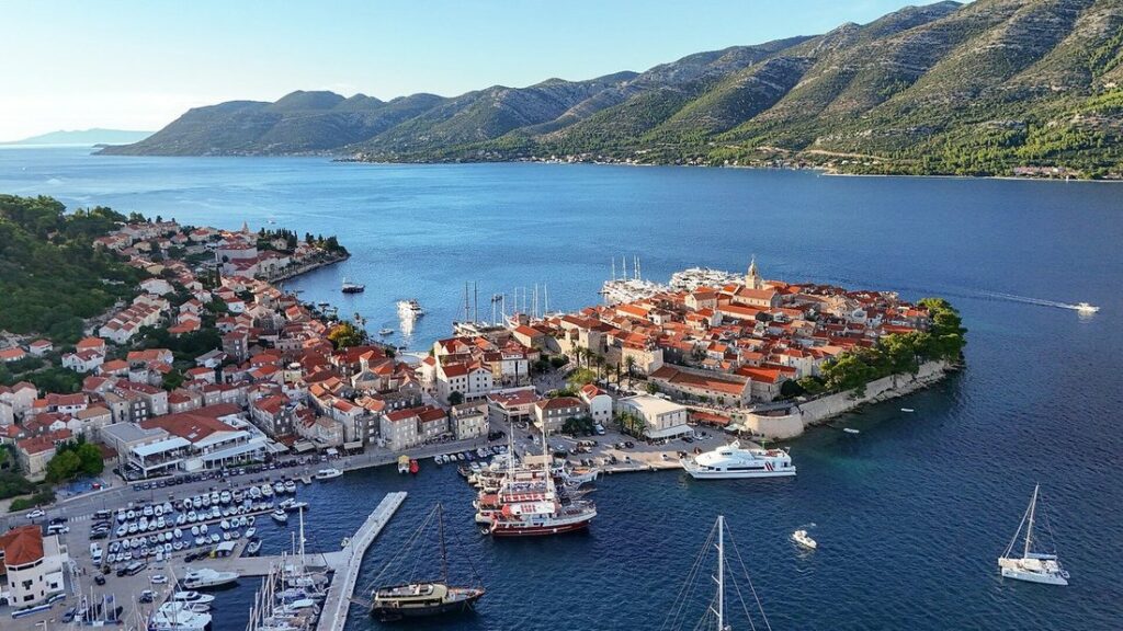 Vue aérienne de la vieille ville de Korčula, un promontoire de toits orange entouré de remparts et d'eau bleue