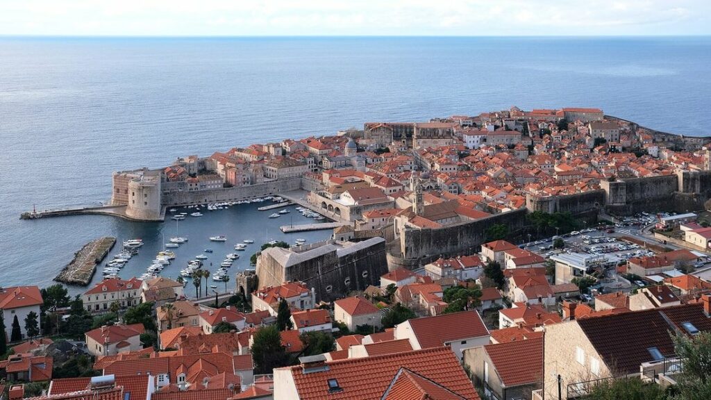 Vue aérienne de la vieille ville de Dubrovnik : toits orange, remparts et vieux port au bord de l'Adriatique