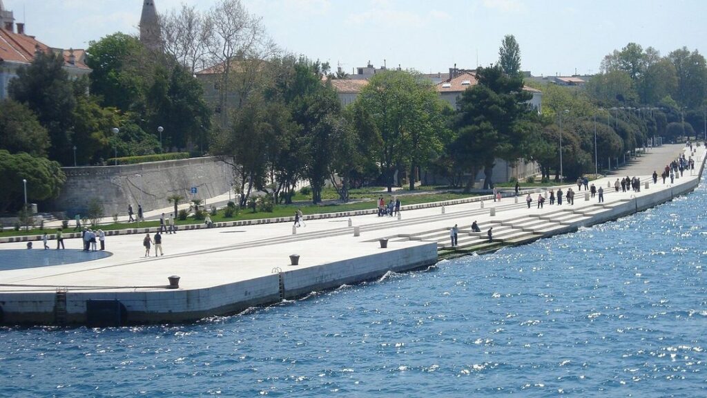 Promenade et marches de pierre blanche au bord de la mer à Zadar, avec des promeneurs et une eau bleue
