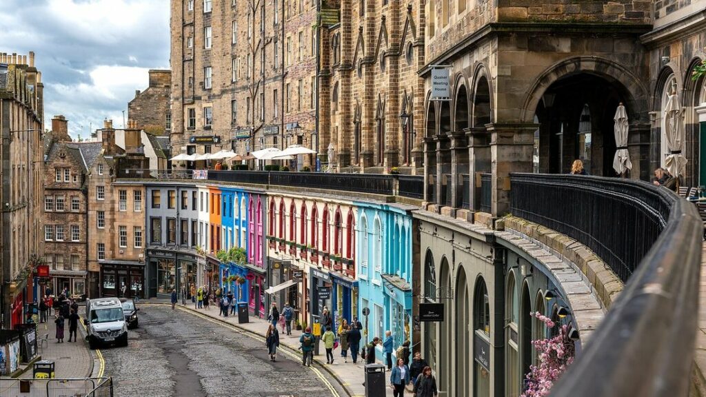 Rue incurvée de la vieille ville d'Édimbourg bordée de boutiques aux façades colorées et d'immeubles en pierre
