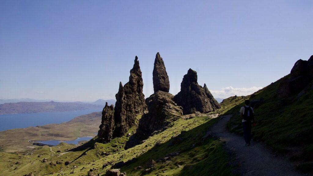 Pitons rocheux de l'Old Man of Storr sur une crête herbeuse, avec la mer au loin