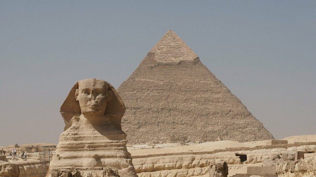 Le Sphinx de Gizeh au premier plan devant la pyramide de Khéphren, sous un ciel voilé