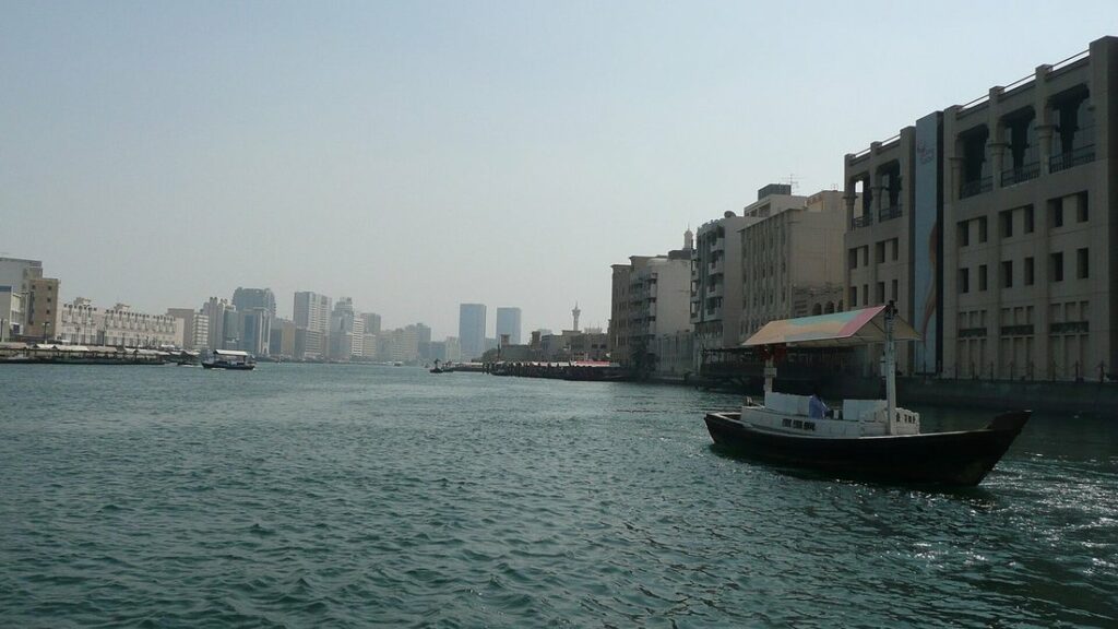 Abra, petit bateau en bois, sur la crique de Dubai, avec des immeubles bas et des tours au bord de l'eau