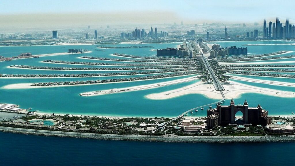 Vue aérienne de Palm Jumeirah, île artificielle en forme de palmier, avec un grand hôtel et la skyline de Dubai au fond