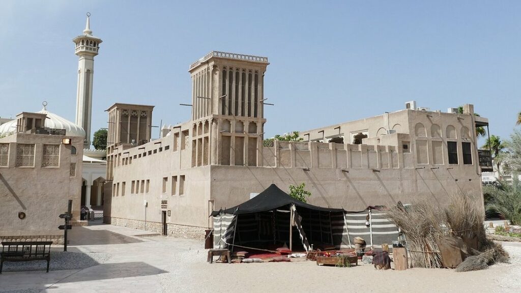 Tour à vent, minaret et maisons de pierre claire du quartier historique d'Al Fahidi, avec une tente noire au pied