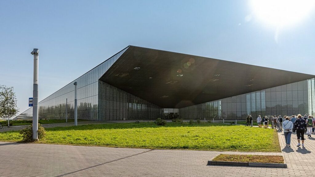 Longue façade vitrée et grand toit incliné du musée national estonien, avec une pelouse au premier plan