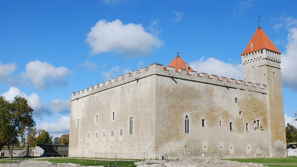 Château de Kuressaare en pierre claire, avec ses tours à toit rouge, sous un ciel bleu nuageux
