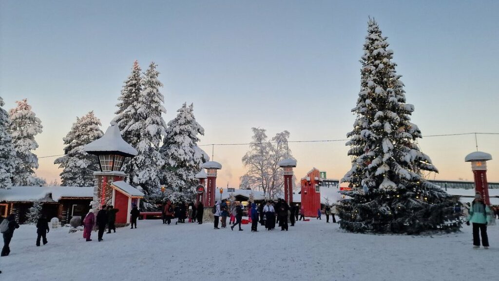 Village couvert de neige avec un grand sapin, des bornes rouges et de petits chalets en bois