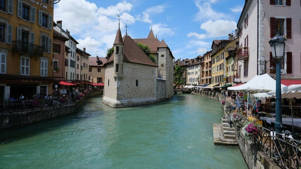 Petit édifice de pierre au toit pointu au milieu d'un canal bordé de façades colorées