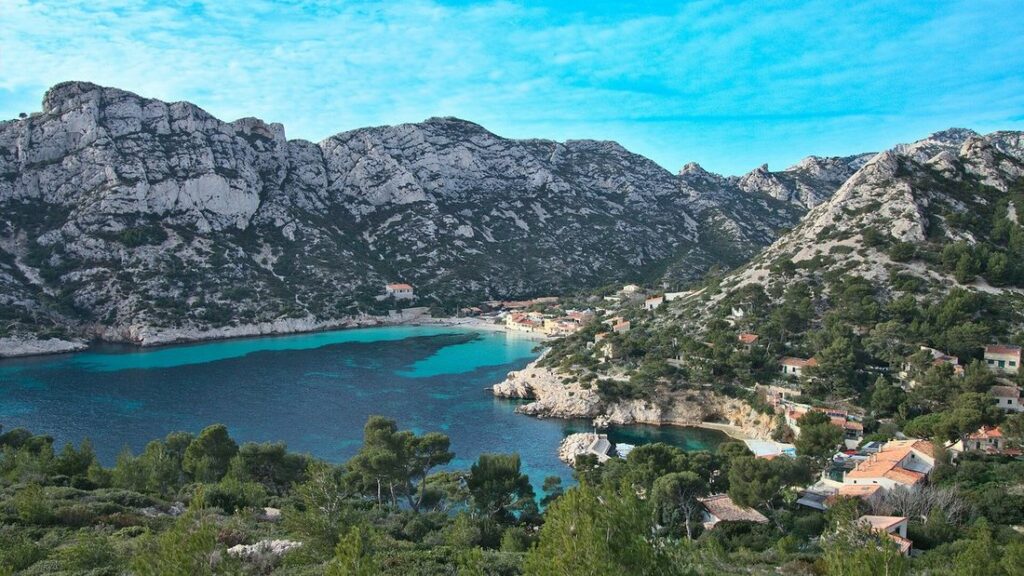 Crique aux eaux turquoise entre des falaises de calcaire clair, avec quelques maisons au bord de l'eau