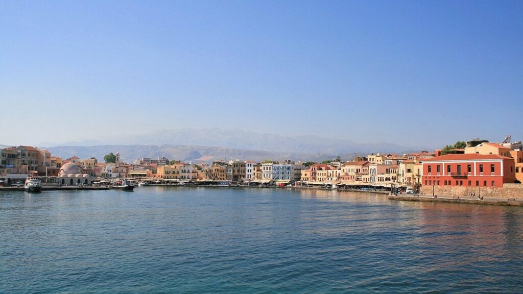 Port vénitien de La Canée, façades colorées alignées sur le quai et mer calme sous un ciel bleu