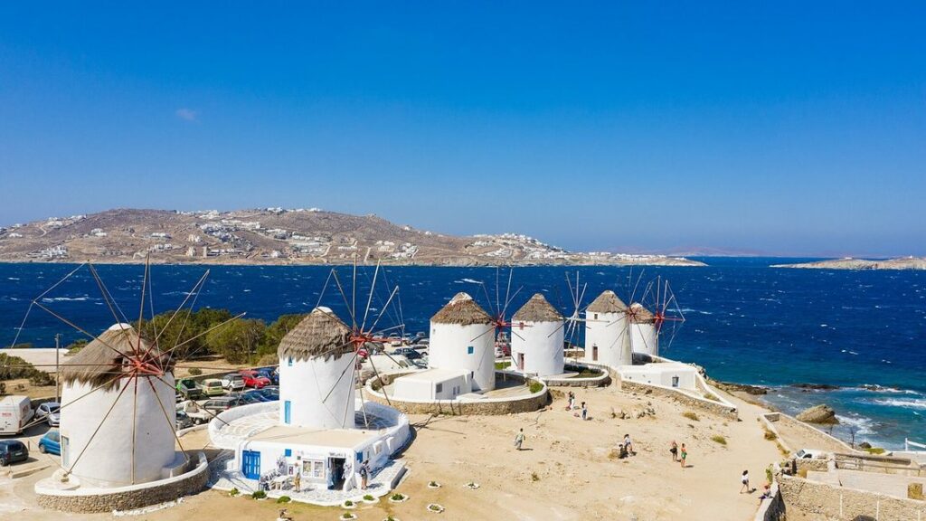 Moulins à vent blancs à toit de chaume de Mykonos, vus d'en haut, au bord d'une mer bleu profond