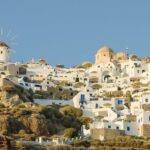 Maisons blanches et dômes d'églises d'Oia serrés sur la falaise de Santorin, avec un moulin à vent