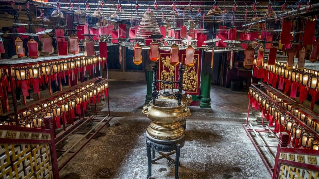 Intérieur du Man Mo Temple, avec des lanternes rouges, des spirales d'encens suspendues et un brûle-encens doré