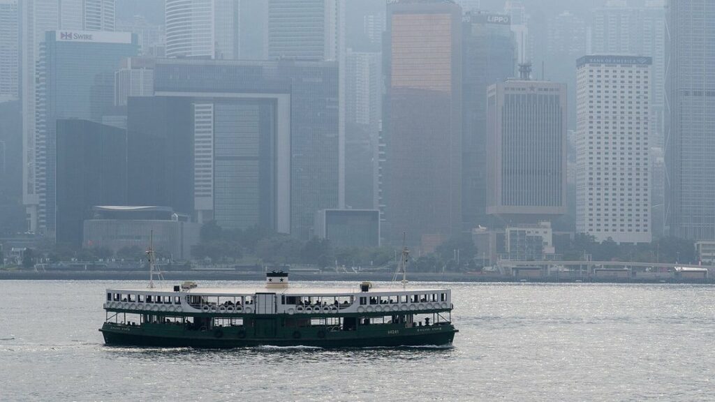 Un Star Ferry blanc et vert traverse le port Victoria, avec les tours de Hong Kong Island dans la brume