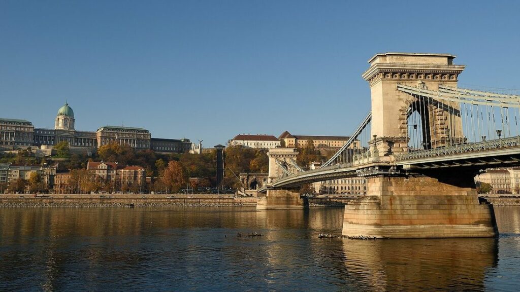 Pont suspendu à piles de pierre au-dessus du Danube, avec le palais royal sur la colline de Buda en arrière-plan