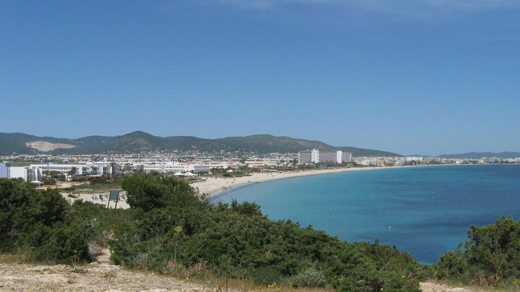 Vue sur la longue baie de Playa d'en Bossa, sa plage de sable, ses immeubles et les collines au fond