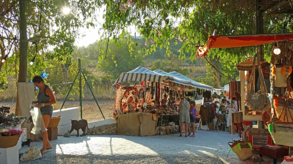 Allée ombragée du marché de Las Dalias, avec des étals d'artisanat sous les arbres et quelques visiteurs