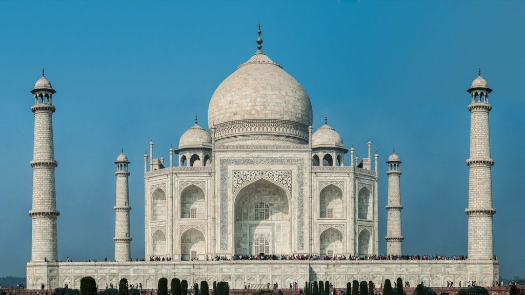 Le Taj Mahal, mausolée de marbre blanc à dôme central entre quatre minarets, sous un ciel bleu
