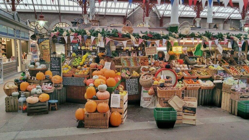 Étals de fruits et légumes sous la verrière métallique du marché couvert de Saint-Hélier