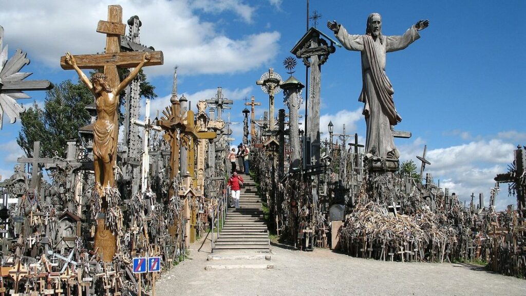 Allée et marches entre des milliers de croix de bois et de métal, avec des statues du Christ